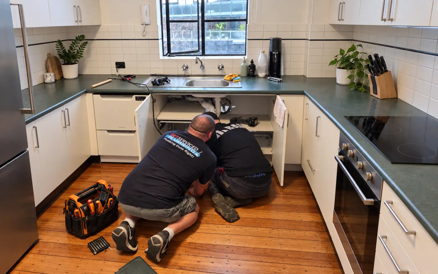 Oakleigh plumber 15 Get Serviced Plumbing team repairing pipework underneath a kitchen sink